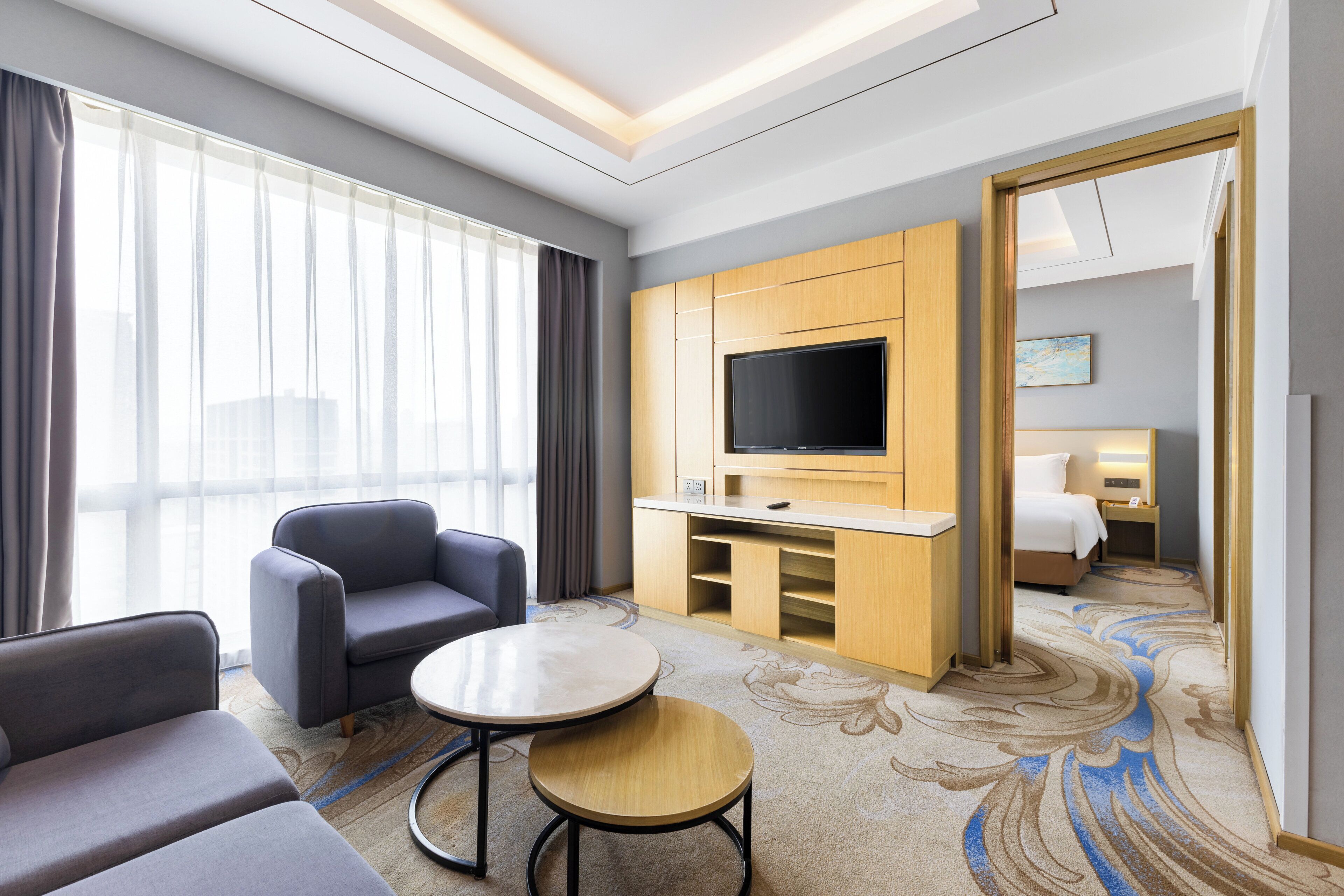 Ein Hotelzimmer mit einer Couch, einem kleinen runden Tisch, einem Fernseher und einem Bett.