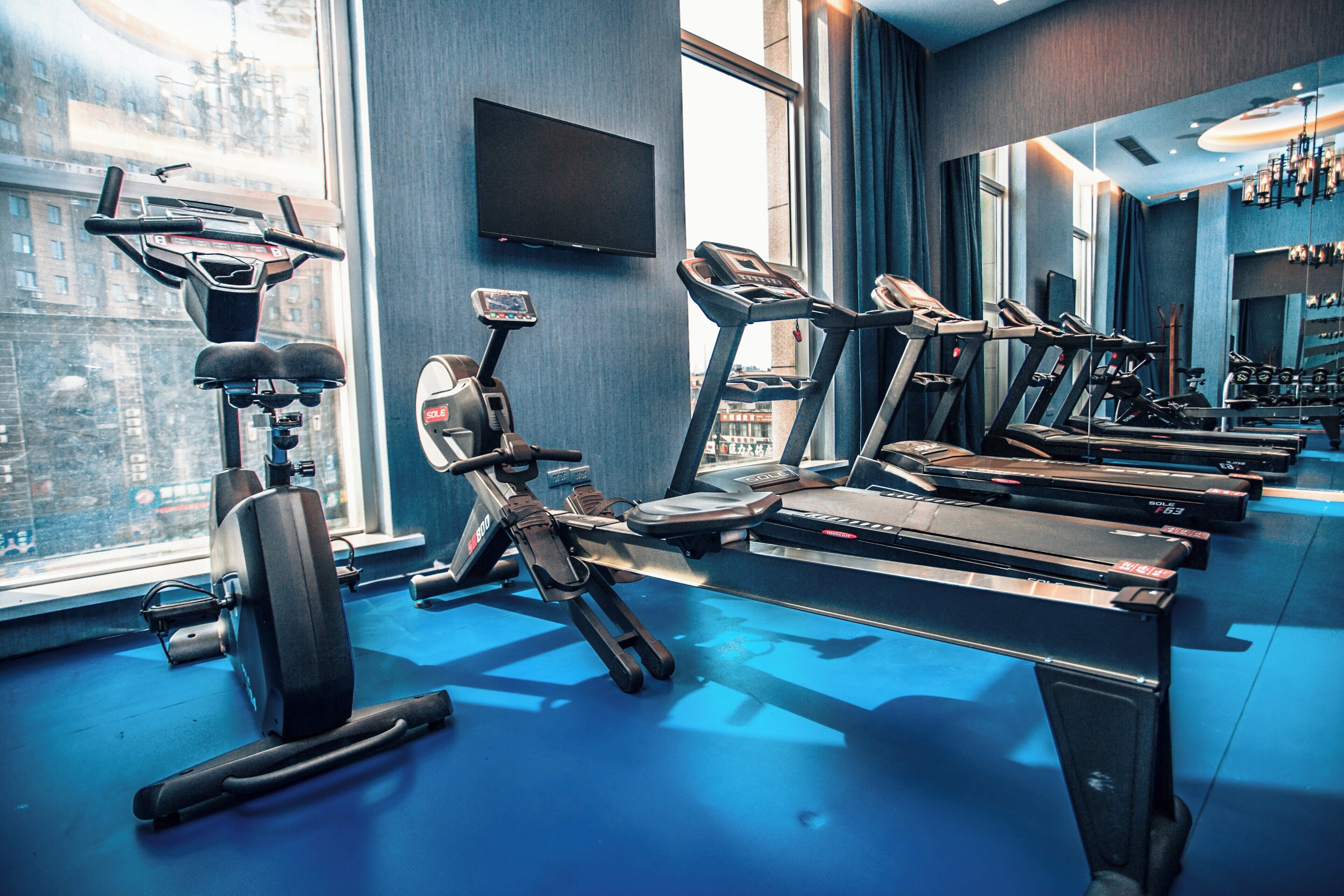 Ein Fitnessstudio mit mehreren Laufbändern, Ergometer und einem Rudergerät.