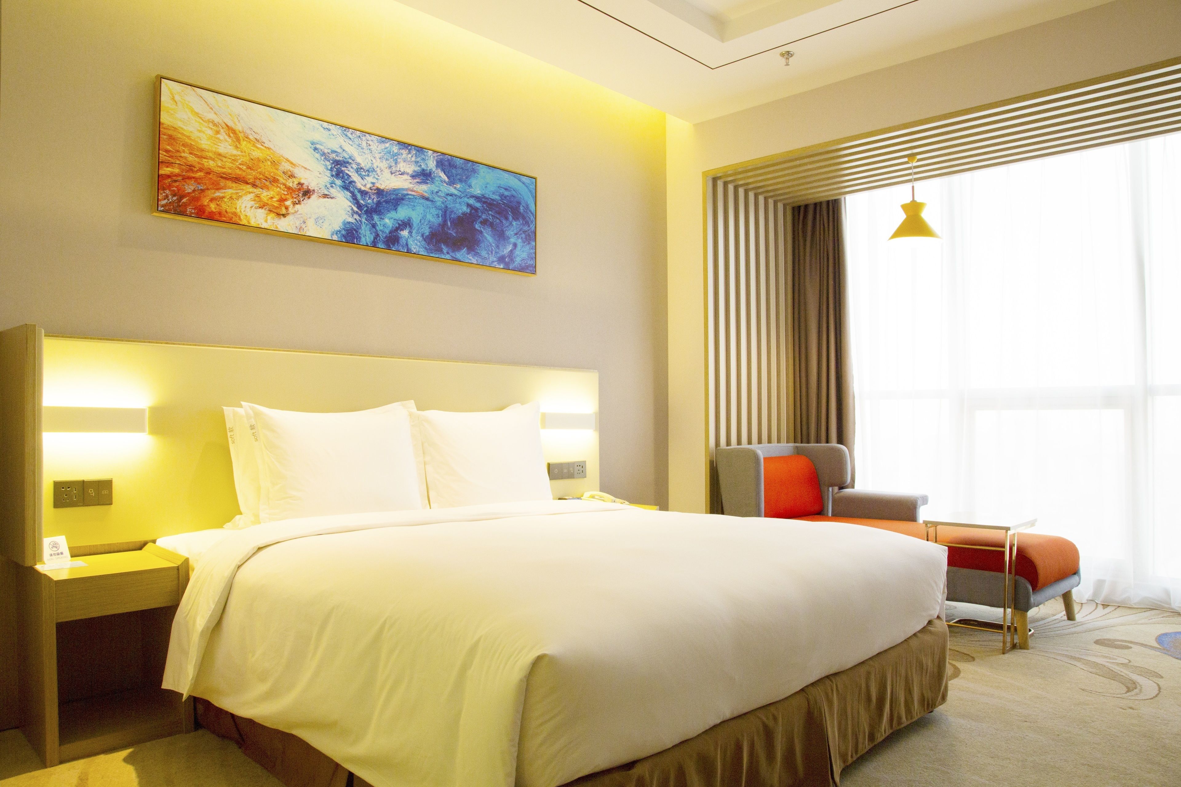Habitación de hotel con una cama grande, lámparas de noche, una silla, una ventana con cortinas y un cuadro en la pared.