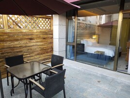 Una habitación de hotel con una cama grande, una mesita pequeña y un ventanal que da al balcón.
