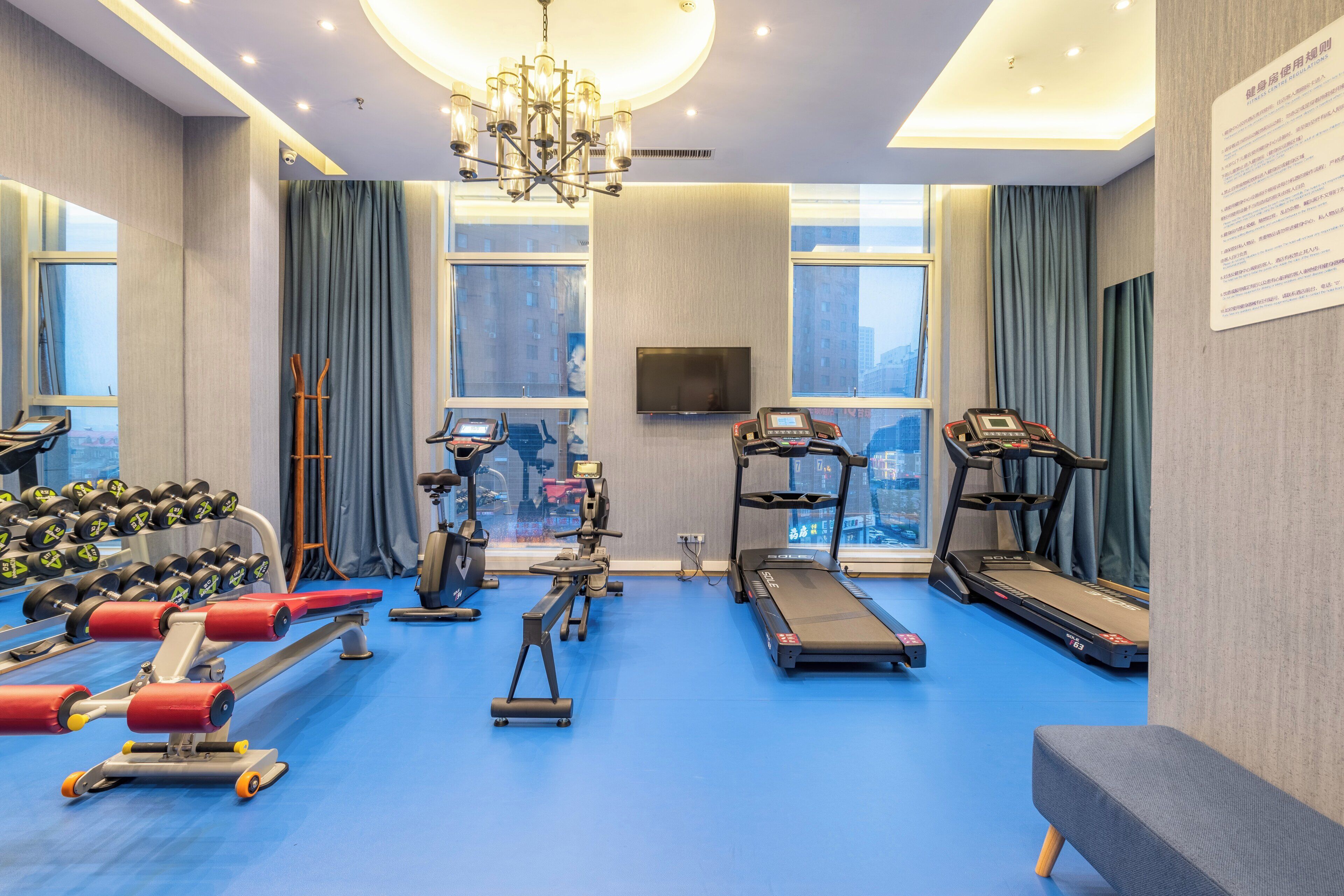 A gym with exercise equipment, a treadmill, and a bench.