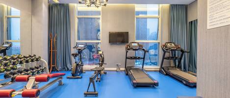 A gym with exercise equipment, a treadmill, and a bench.