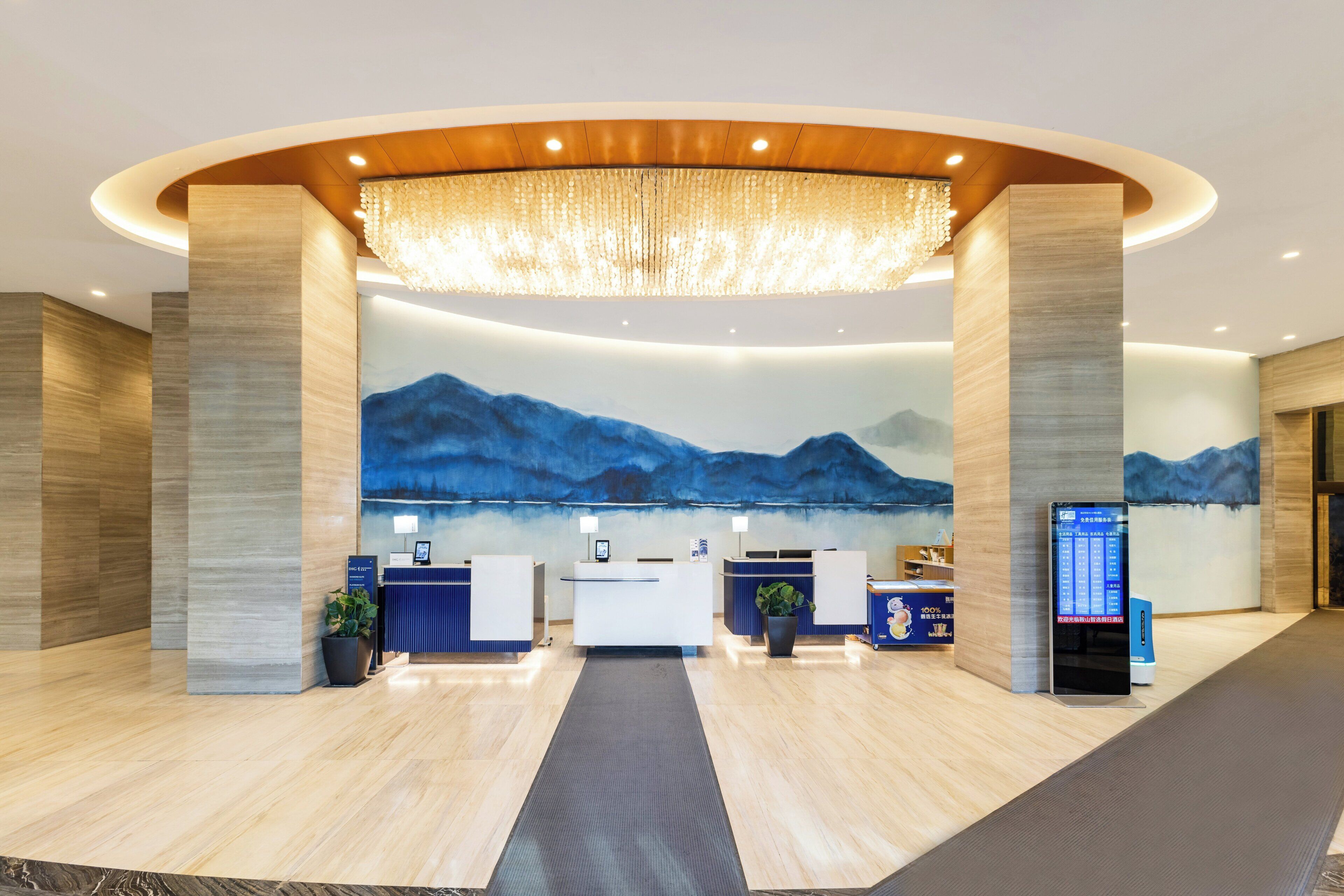 A modern reception area with a large mural of mountains, a reception desk, and a digital information kiosk.