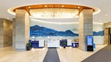 A modern reception area with a large mural of mountains, a reception desk, and a digital information kiosk.