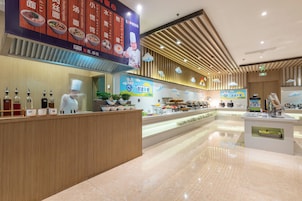 A modern restaurant interior with a buffet setup, wooden paneling, and a chef's station.
