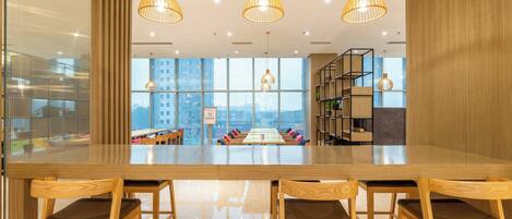 A modern interior with a long wooden table, four wooden chairs, and three hanging pendant lights.