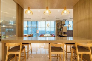 Un intérieur moderne avec une longue table en bois, quatre chaises en bois et trois lampes suspendues.