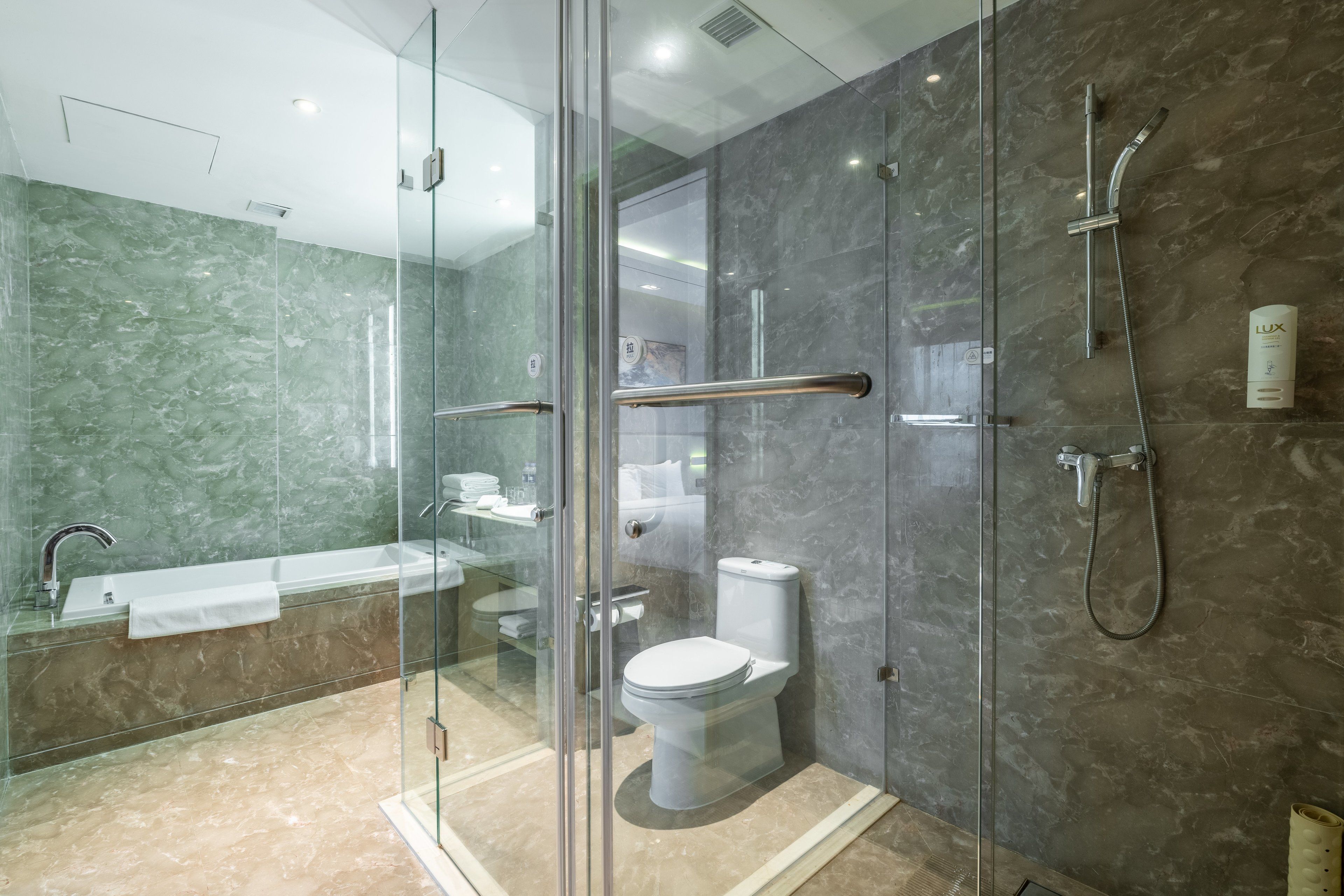 A modern bathroom with a glass-enclosed shower, a white bathtub, and a toilet.