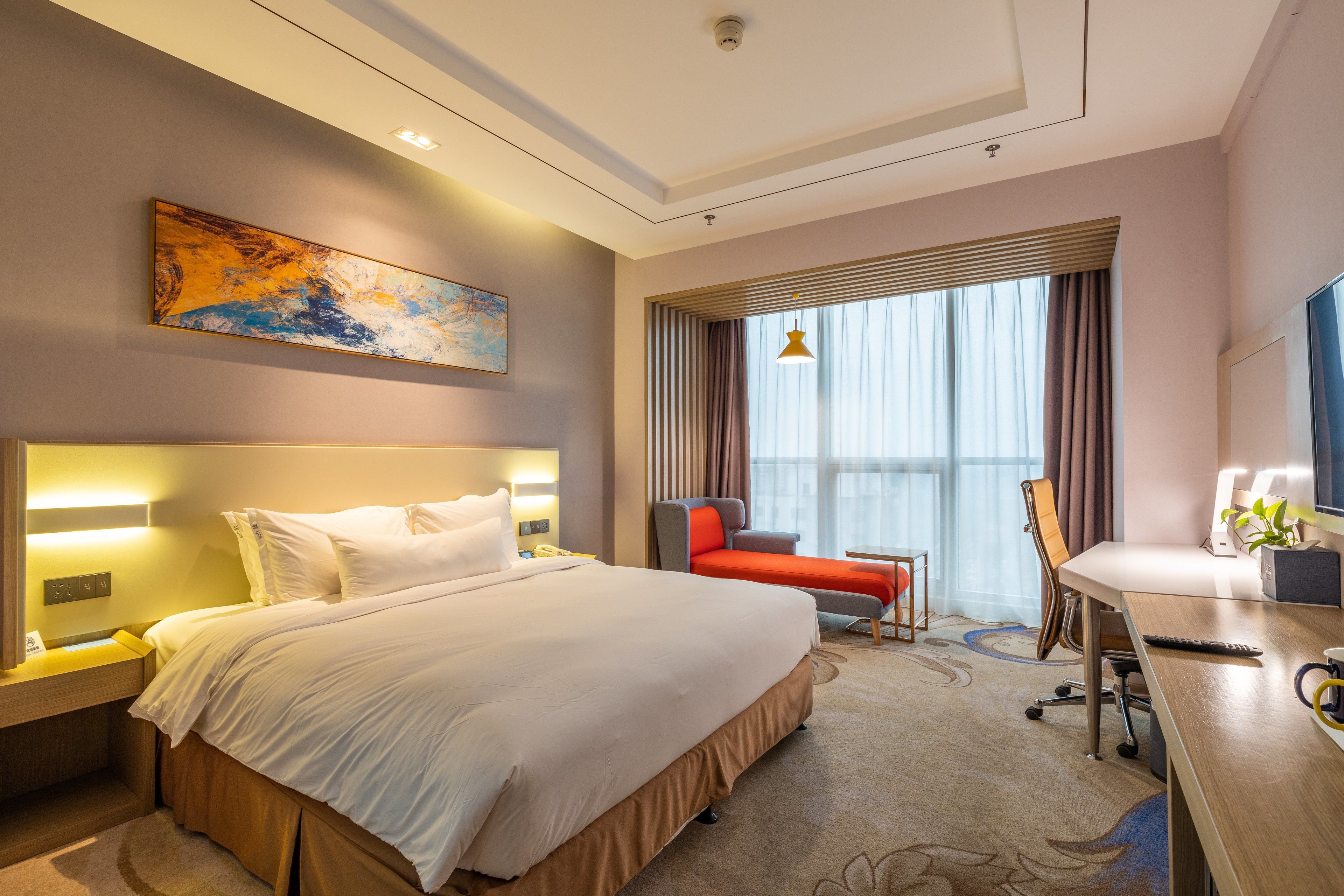 Habitación de hotel con una cama grande, un escritorio con ordenador, una silla, un televisor y una ventana con cortinas.