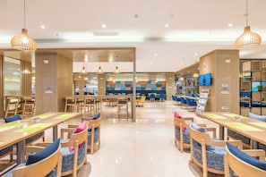 Un restaurante moderno con mobiliario de madera, un área de estar central y una pantalla de televisión.