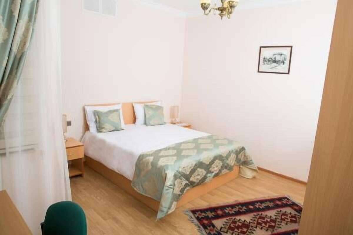 Une chambre à coucher avec un lit, des tables de chevet, une chaise, un tapis et un tableau au mur.