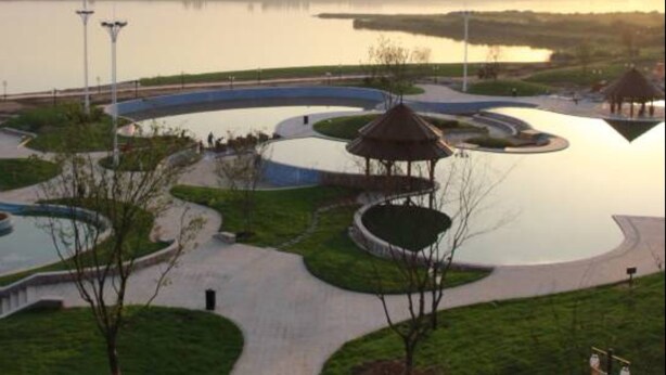 Un parco con un elemento d'acqua circolare, vialetti e un padiglione.