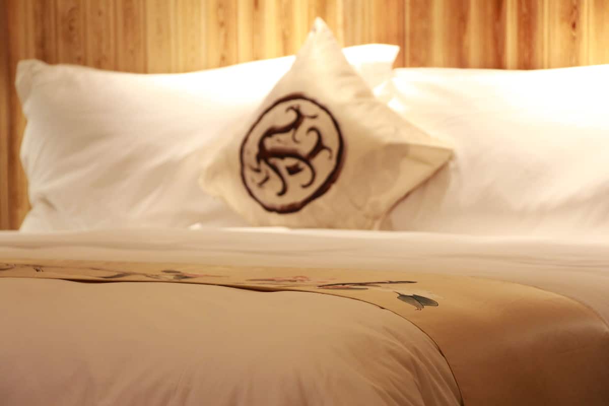 Una cama con una colcha de estampado floral y una almohada con un emblema circular.