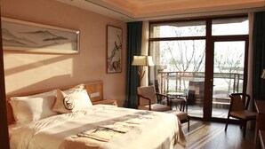 Una camera d'albergo con un letto grande, una scrivania con una sedia, una finestra vista esterna e un quadro appeso al muro.