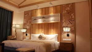 Camera da letto con un letto, comodini, lampade e una parete decorata con motivi floreali e immagini di uccelli.