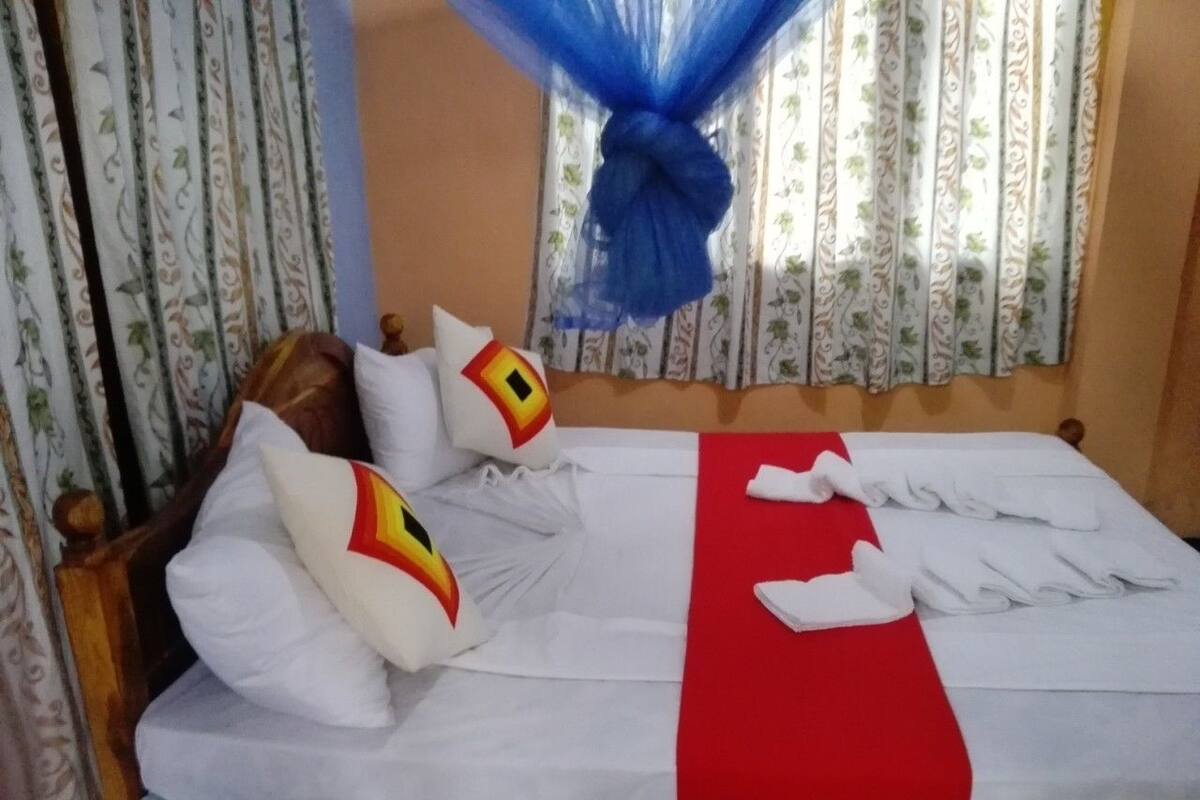 A neatly made bed with white and red bedding, a teal skirt, and a blue canopy.