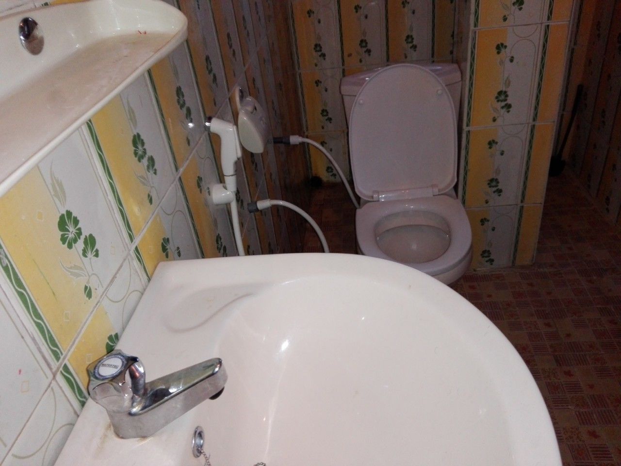 A bathroom with a white sink, toilet, and patterned tiles.