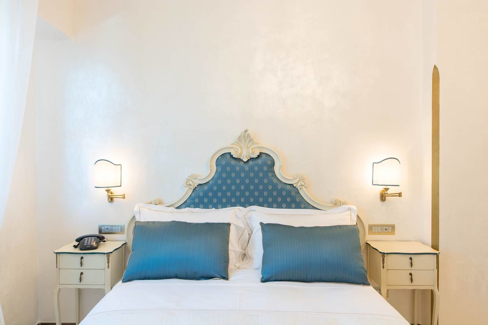 Ein Hotelzimmer mit einem großen Bett, zwei Nachttischen, einem Telefon und Wandlampen.