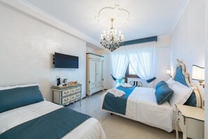 Une chambre avec deux lits, une commode, un téléviseur et un lustre.
