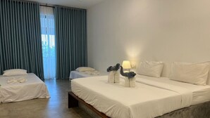 Une chambre d’hôtel avec un grand lit, un plus petit lit et un banc. Il y a une fenêtre avec des rideaux et une lampe sur le plus petit lit.