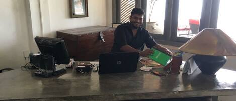 A person seated at a desk with a laptop, papers, and a green folder.