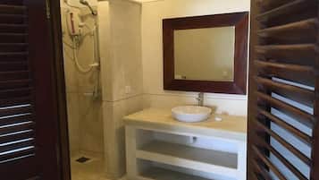 A bathroom with a shower, a sink with a mirror, and wooden slatted doors.