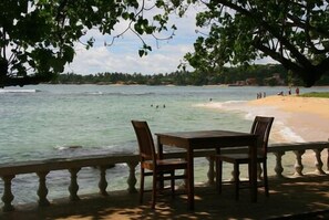 Enjoy breathtaking views of the calm sea from this beachfront balcony, featuring a table and chairs for a relaxing outdoor space.