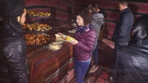 Um grupo de pessoas em um buffet com diversos pratos expostos em estantes.