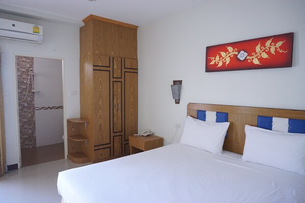 A hotel room with a large bed, wooden wardrobe, and a wall-mounted artwork. - UD Residence (Udon Thani)