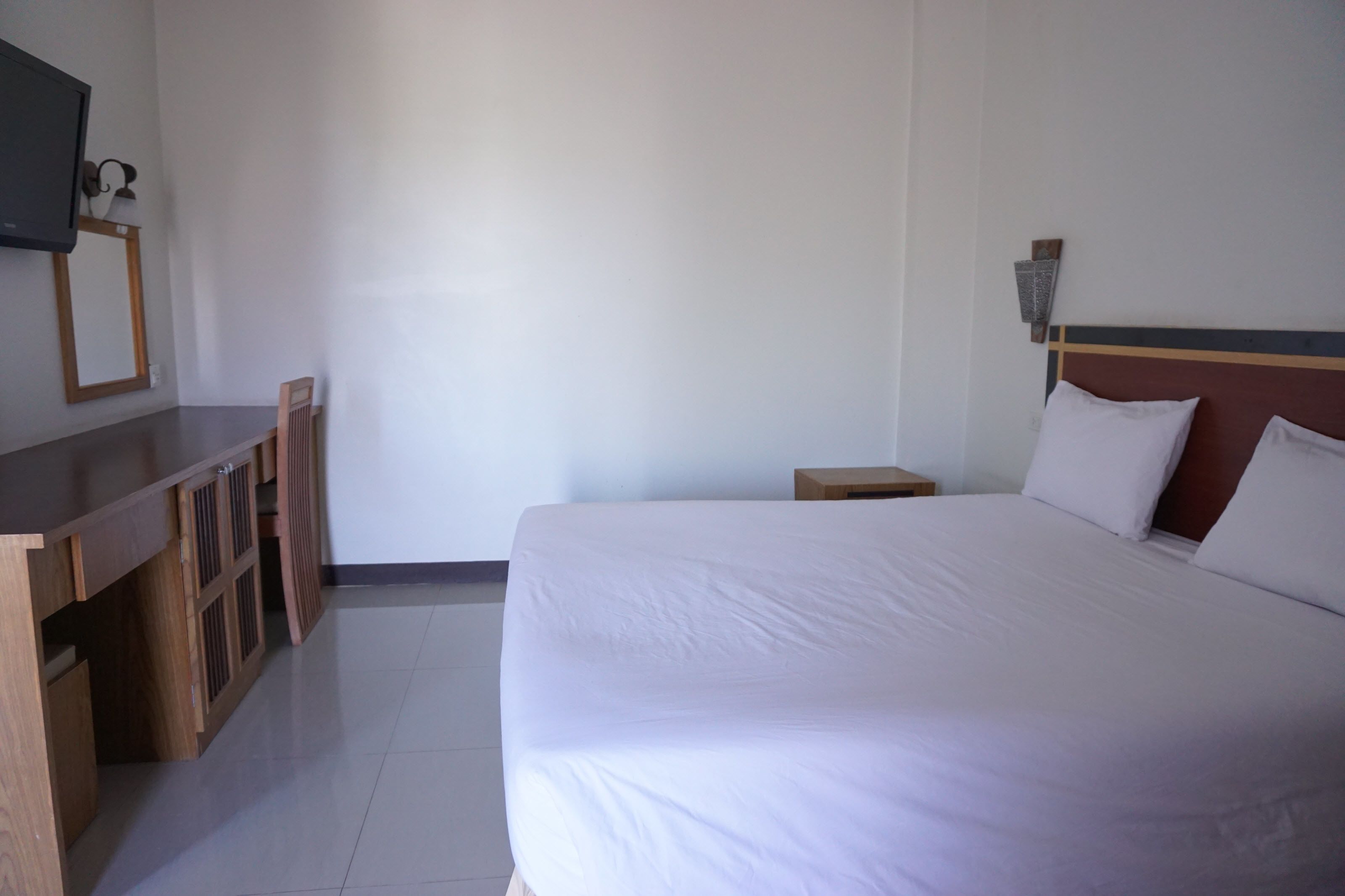 Une chambre d’hôtel équipée d’un lit, d’un bureau, d’une chaise, d’une télévision et d’une table de chevet.