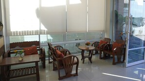 A sunlit room with a glass door, wooden furniture, and a view of the outside. - UD Residence (Udon Thani)