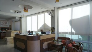 A reception area with a counter, chairs, and a table. - UD Residence (Udon Thani)