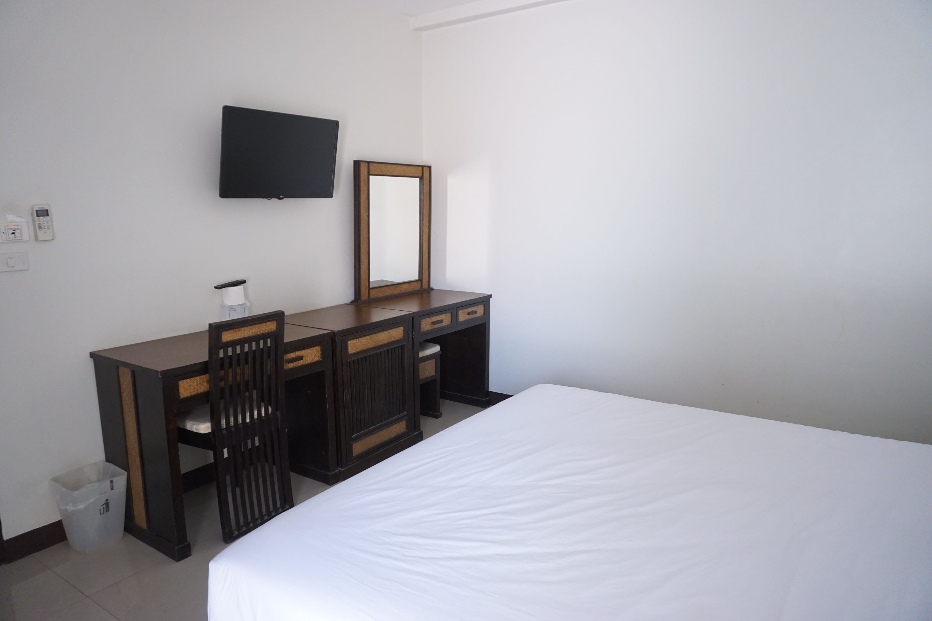 A hotel room with a bed, a desk with a chair, a television, and a mirror.