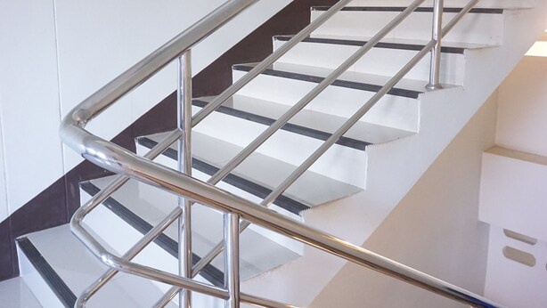 A modern staircase with a metal handrail and wooden steps. - Chanprasert House (Udon Thani)
