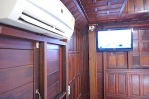 Una habitación con paneles de madera, televisor montado y aire acondicionado.