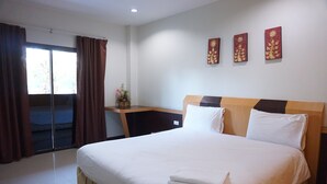A hotel room with a large bed, a desk, and a sliding door to the outside. - Chanprasert House (Udon Thani)