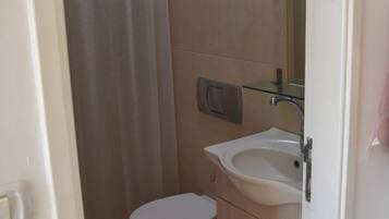 A small bathroom with a toilet, sink, and shower curtain.