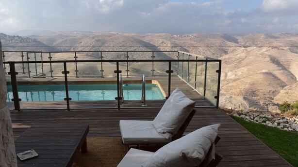 A wooden deck with a glass balustrade overlooking a pool and a mountainous landscape. - Nof Canaan (Nofei Prat)