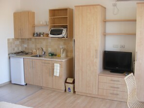 A compact kitchen with a microwave, toaster, sink, and a small refrigerator.