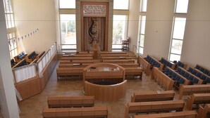 A spacious hall with rows of wooden benches and a central circular area, likely for gatherings or ceremonies. - Nof Canaan (Nofei Prat)