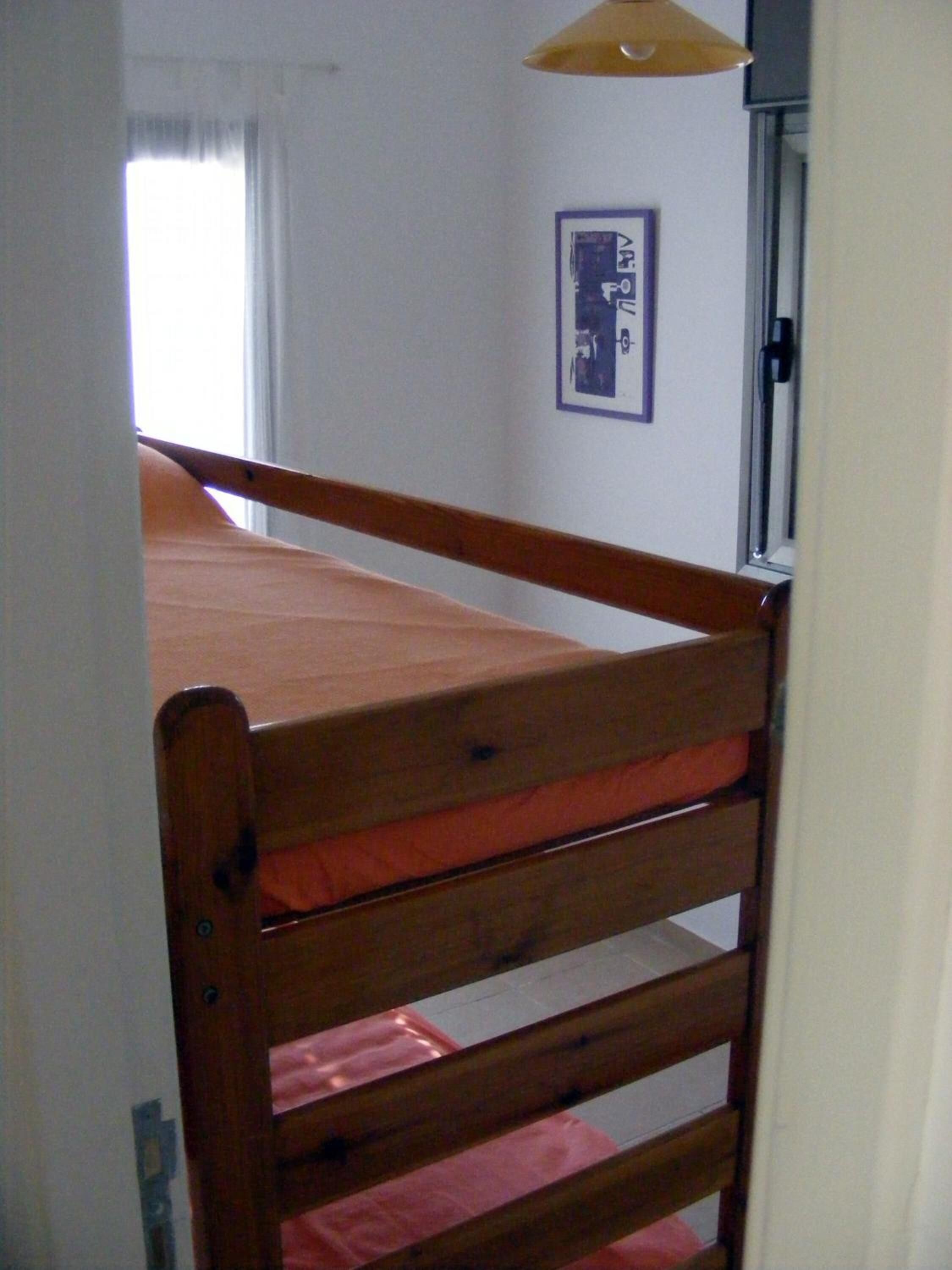 Een kamer met een houten stapelbed, een lijst met een foto aan de muur en een raam met gordijnen.