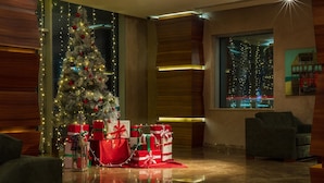 A modern living room with a Christmas tree, presents, and a city view through the window. - Avenue Hotel Baku (Baku)