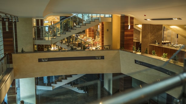 A multi-level interior with glass railings, a central staircase, and a seating area with tables and chairs. - Avenue Hotel Baku (Baku)