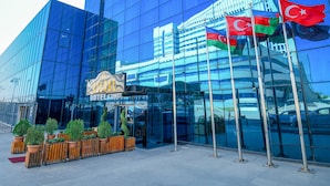 A modern hotel with a glass facade, flags, and a sign that reads "QUENDE HOTEL SMART". - Avenue Hotel Baku (Baku)