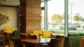 A modern hotel lobby with a seating area, a wooden accent wall, and a view of the street outside. - Avenue Hotel Baku (Baku)