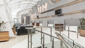 A modern hotel lobby with a curved ceiling, seating areas, a reception desk, and a staircase. - Avenue Hotel Baku (Baku)