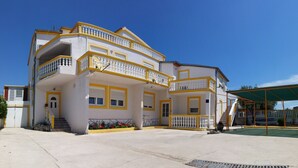 Un immeuble à plusieurs étages doté de balcons, d’un espace extérieur couvert et d’un escalier menant à l’entrée.