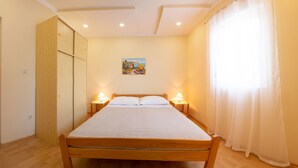 Une chambre à coucher avec un lit en bois, deux tables de chevet avec des lampes, un tableau au mur et une fenêtre avec des rideaux.