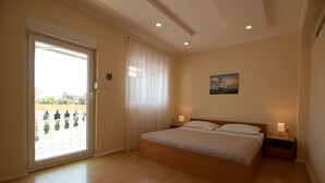 Une chambre à coucher avec un grand lit, une fenêtre avec des rideaux, un tableau au mur et une table de chevet avec une lampe.