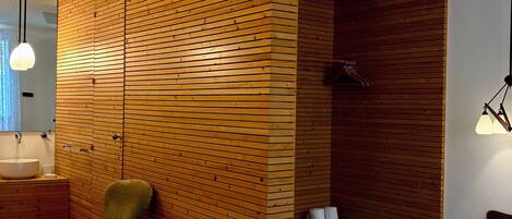 Een moderne kamer met een houten scheidingswand, een bed, een stoel, een klein tafeltje en een bank.